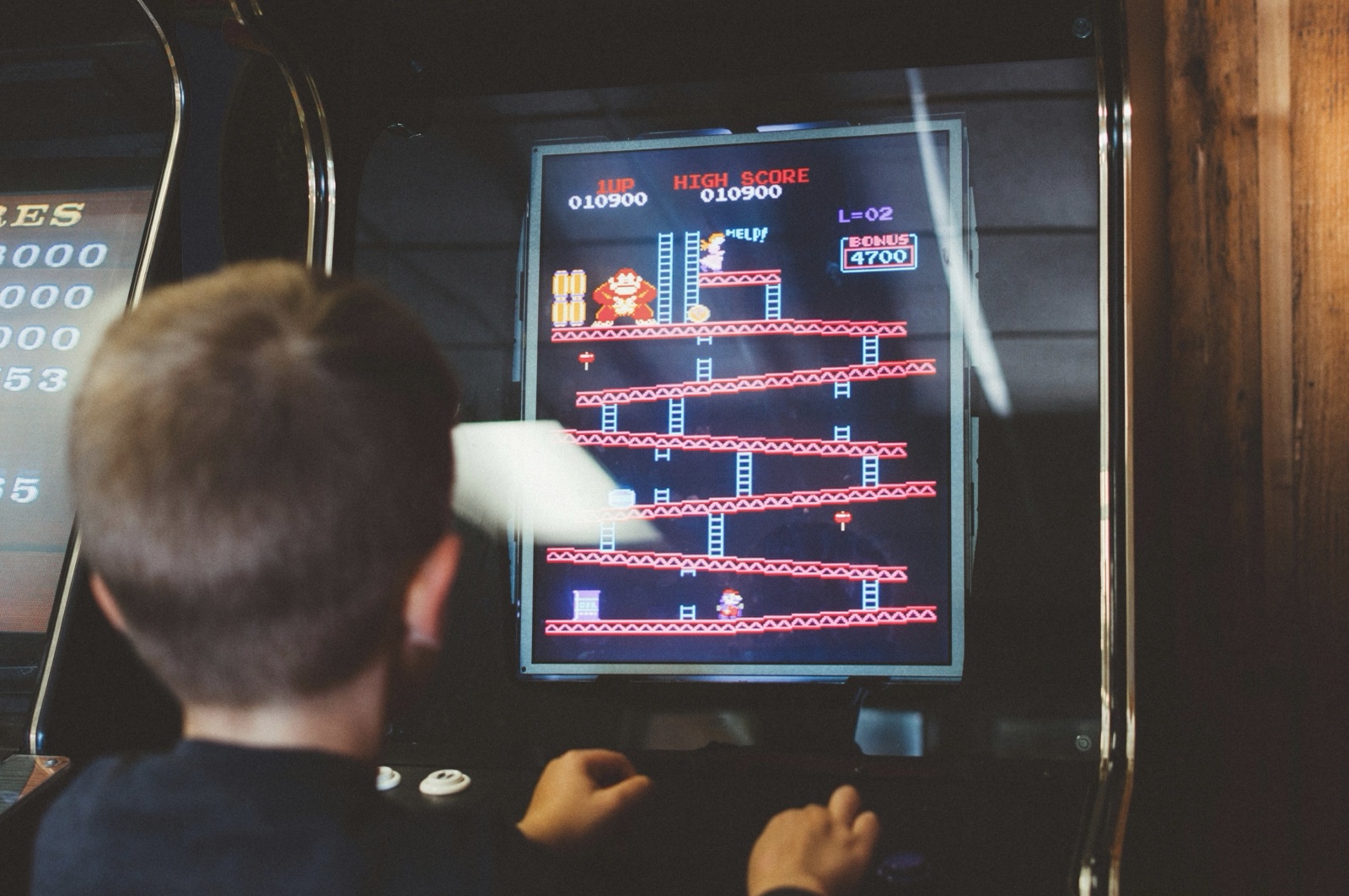 child in front of an 80's arcade cabinet - Donkey Kong