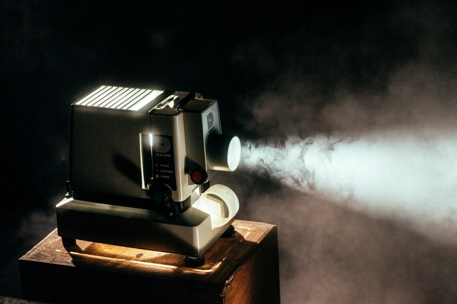 A film projector throwing a beam of light through a dark, smoky room